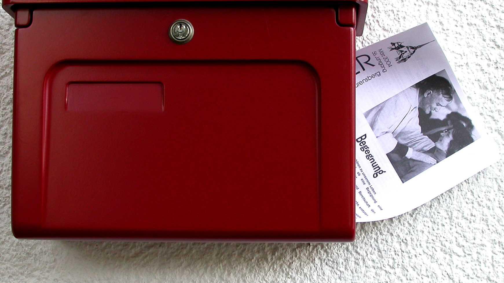 ein Pfarrbrief steckt in einem roten  Briefkasten